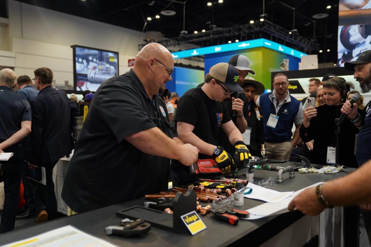 People engaging in a demonstration at Viega's booth at AHR.